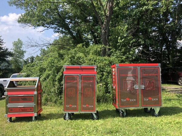 Three red Top Jock horse tack trunks.