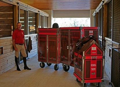 Man stands by equestrian tack trunks.