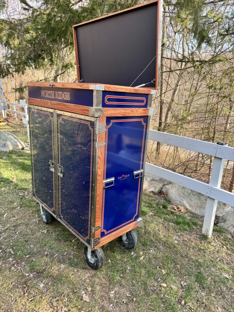 A television cart sitting in the grass near a fence.
